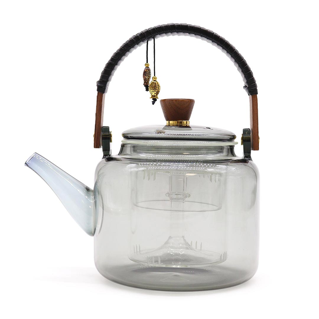 Clear glass teapot with wooden handle and decorative elements on a white background