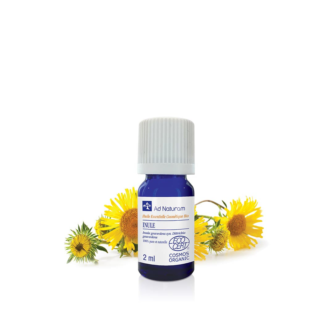 Bottle of Ad Naturam essential oil with yellow Inula flowers on a white background
