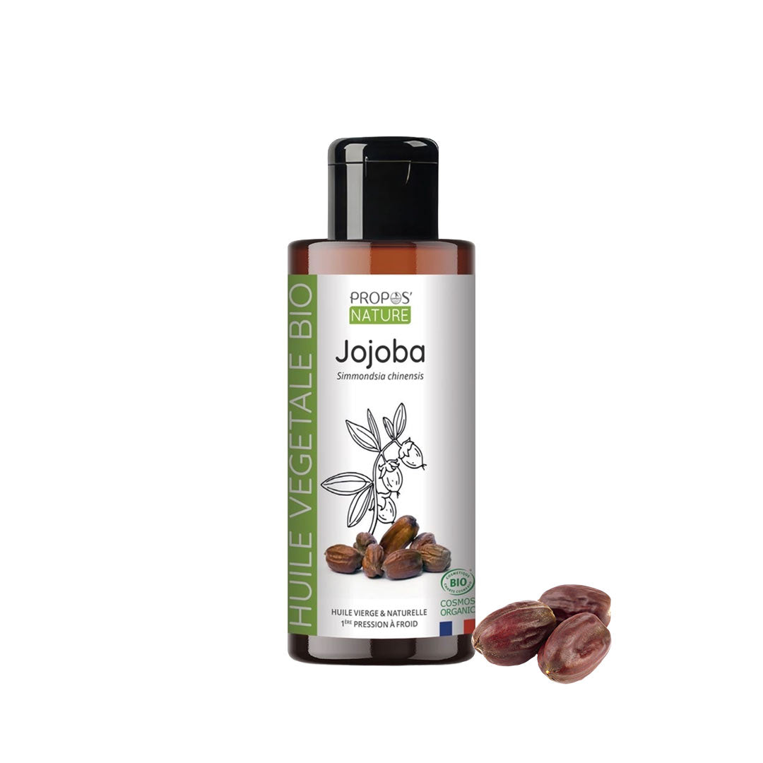 A bottle of Propos Nature Jojoba vegetable oil with a black cap and white label, shown on a white background with a few jojoba seeds next to it.