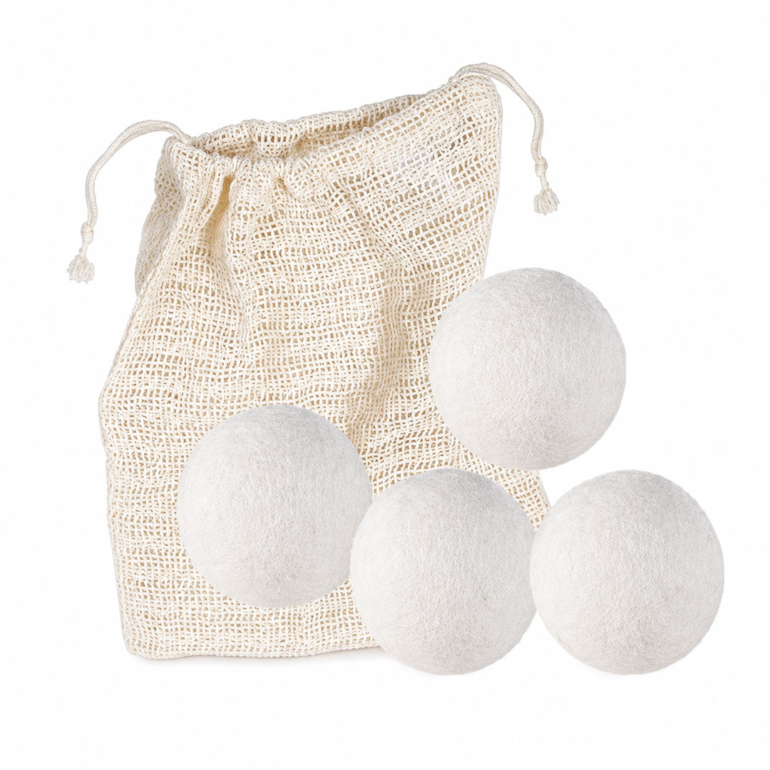 Four white wool dryer balls arranged in front of a natural beige organic cotton drawstring bag on a plain white background.