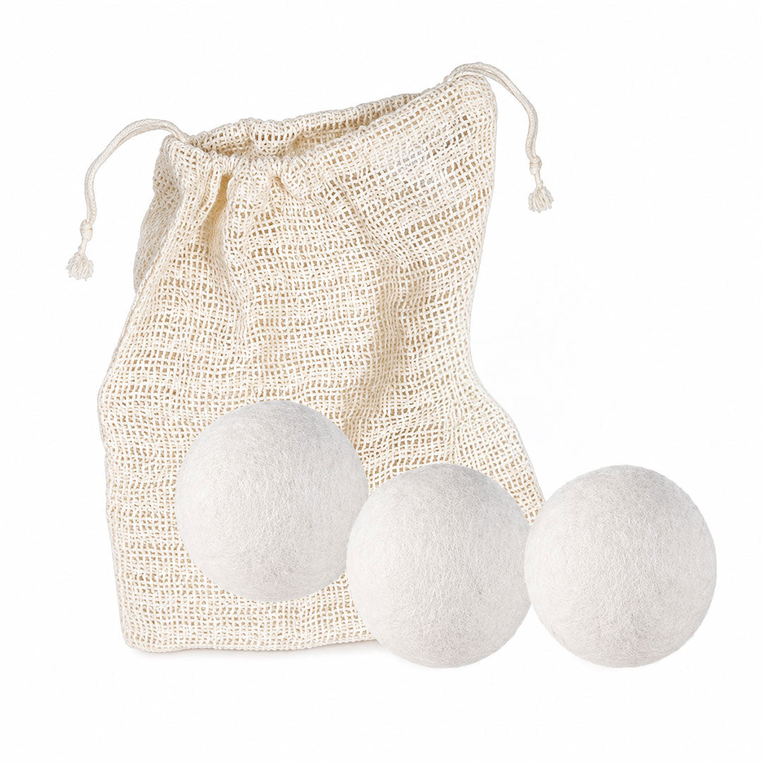 Three white wool dryer balls displayed in front of a natural beige cotton drawstring bag on a clean white background.