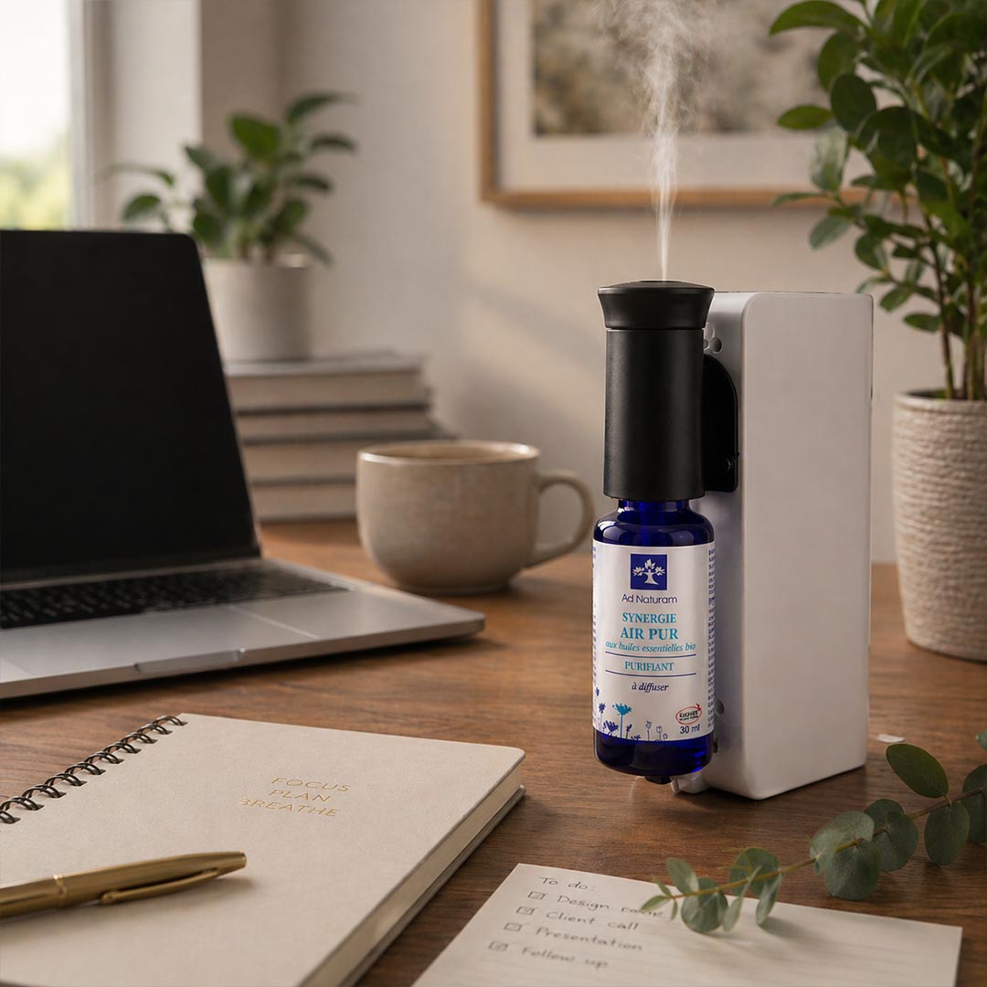 Air purifier on a desk with a laptop, mug, and notebook in a home office setting.