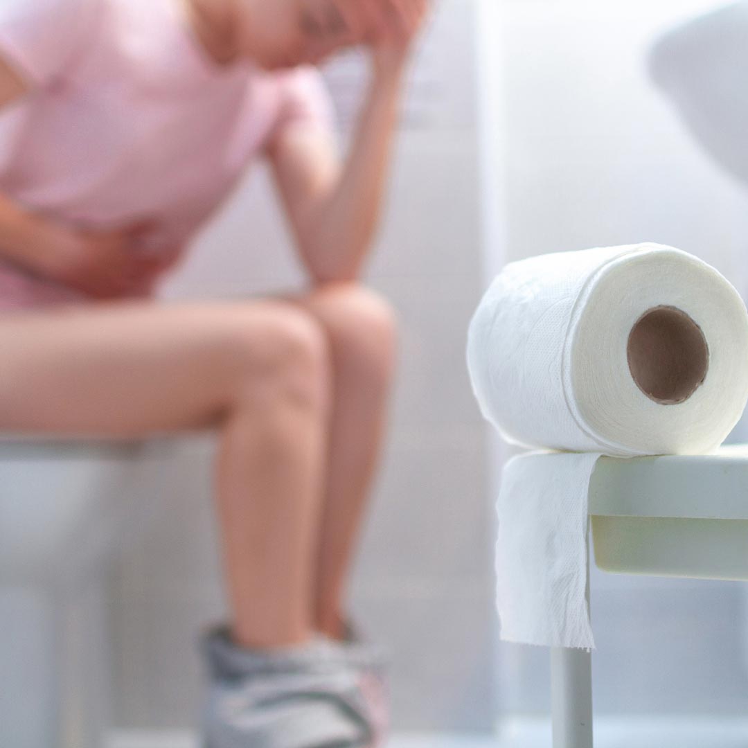 a woman sitting on the toilet having digestive pains