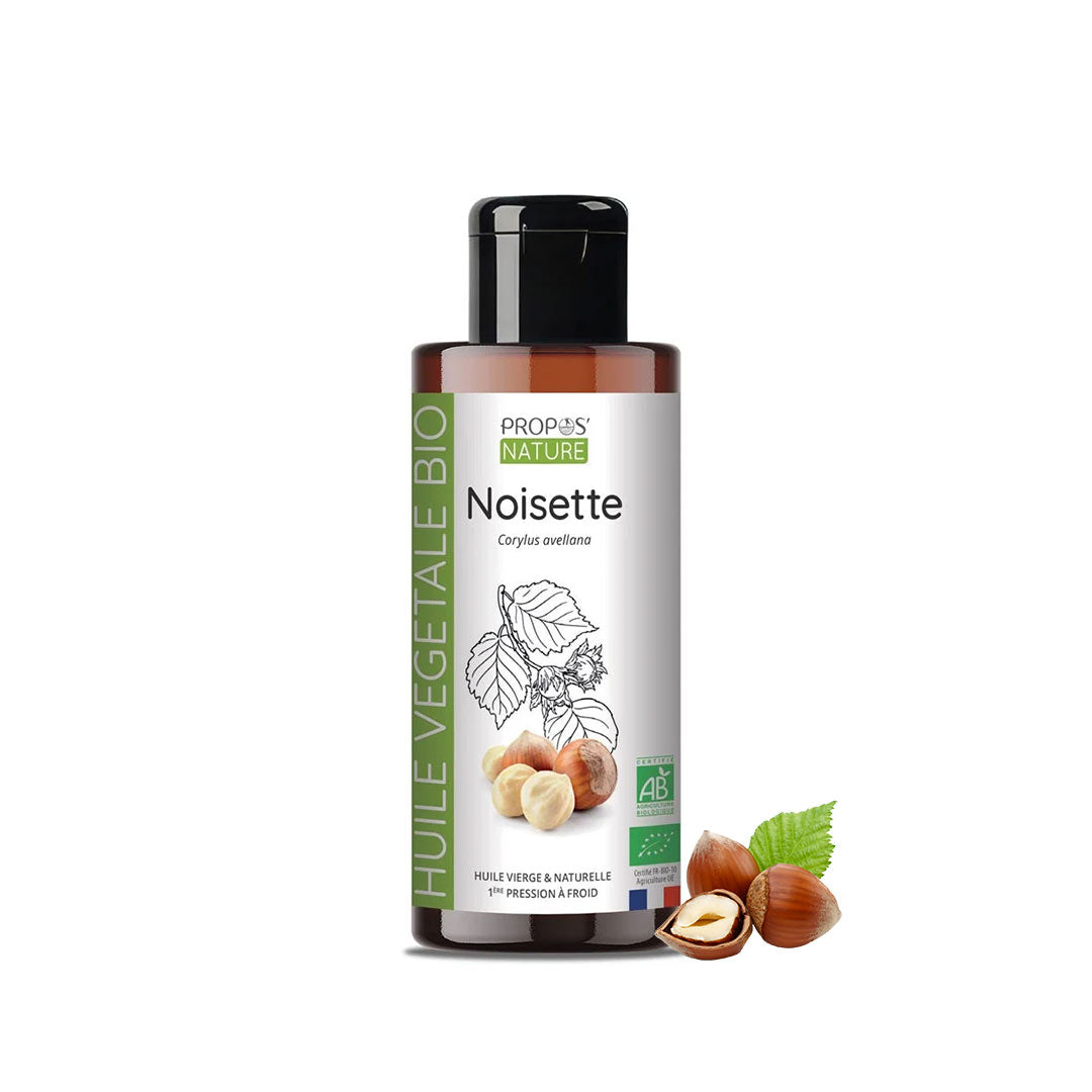A bottle of Propos Nature Bio Noisette (hazelnut) vegetable oil shown with three hazelnuts and a green leaf on a plain white background.