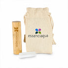 A bamboo essential oil inhaler stick with a natural bamboo cap, shown next to a beige canvas drawstring pouch and a white glass roller bottle. Both items feature the 'essenciagua' brand logo.