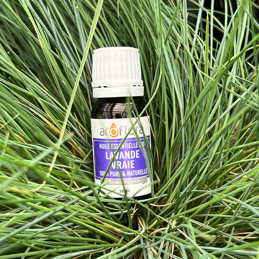 A bottle of organic lavender essential oil from french Aroflora laying in the grass