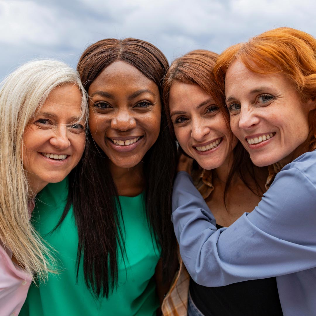 Four women standing together and smiling to the camera