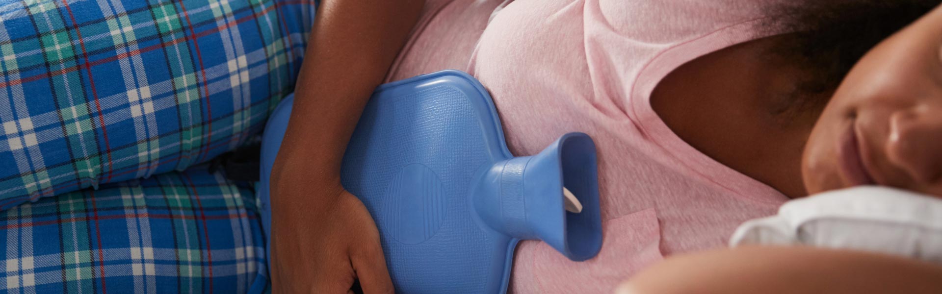 A woman having a warming bottle on her stomach because of pain