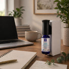 Air purifier on a desk with a laptop, mug, and notebook in a home office setting.