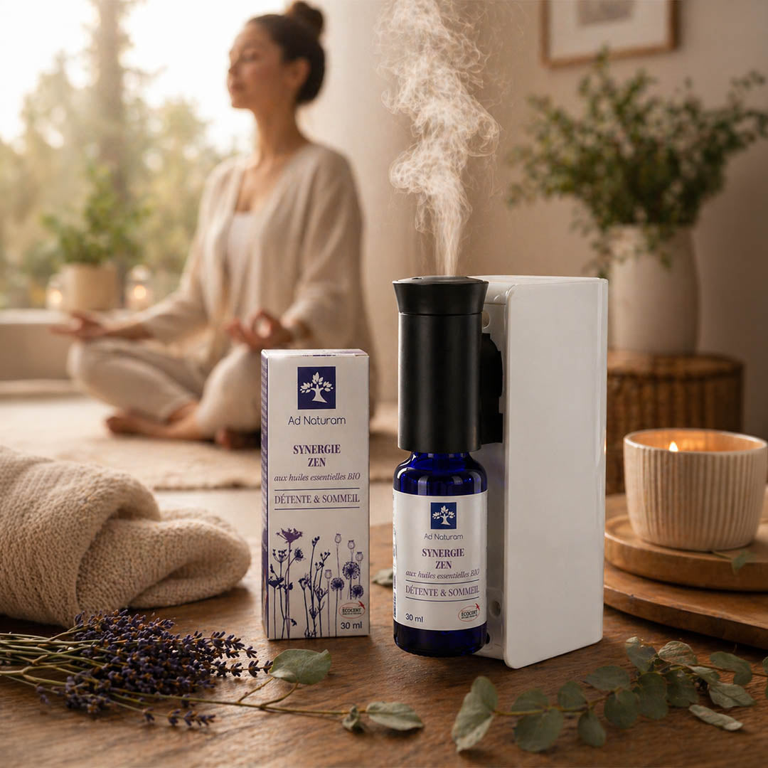 Aromatherapy diffuser and bottle on a wooden surface with a woman meditating in the background.