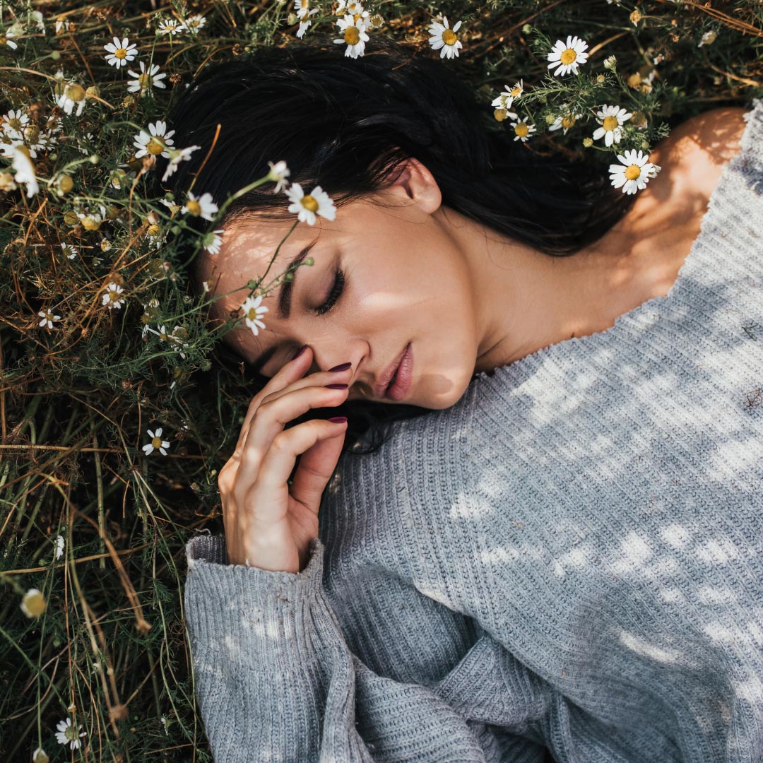 A woman laying in the grass with flowers
