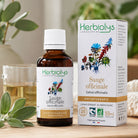 Herbiolys sauge officinale bottle and packaging on a wooden surface with plants in the background
