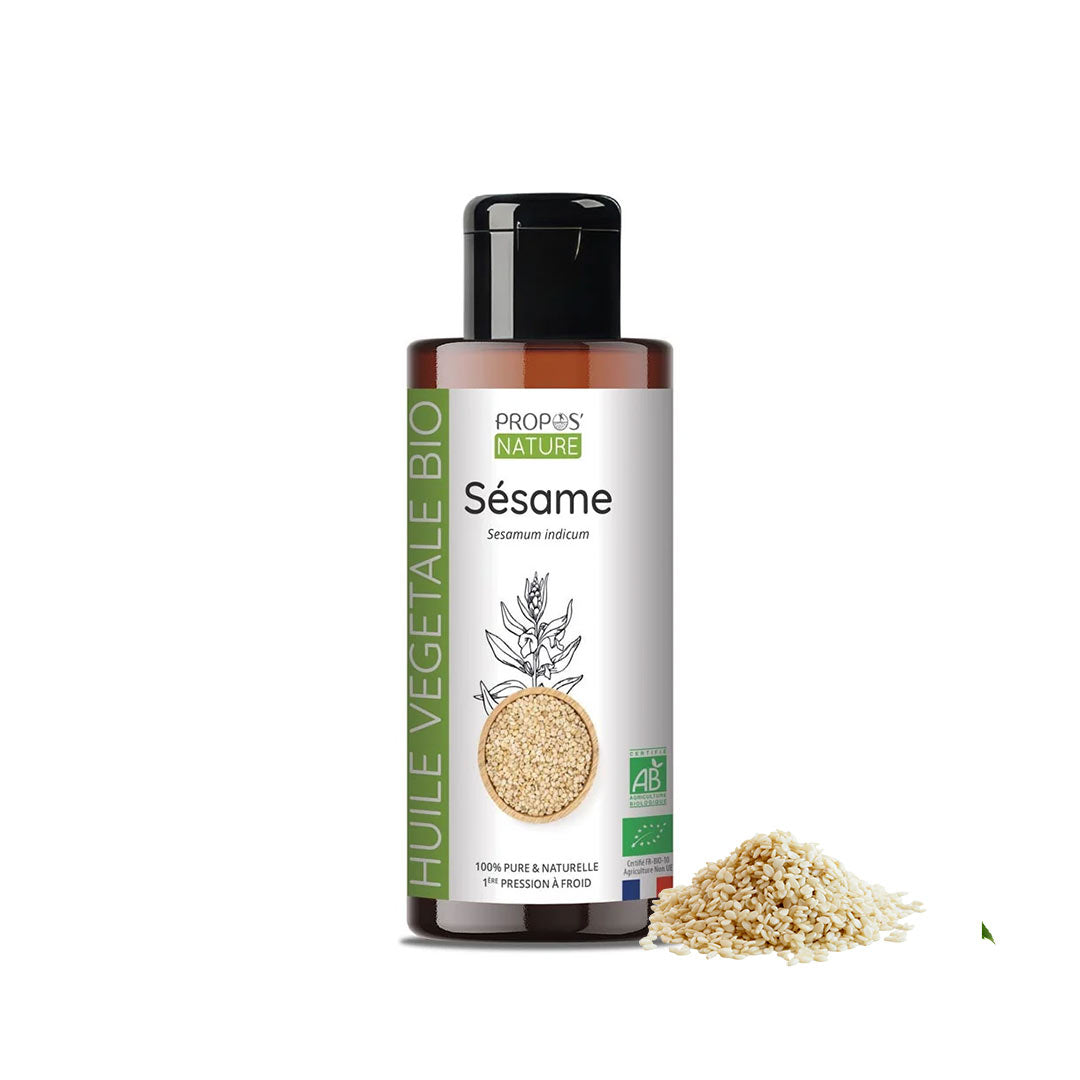 A bottle of Propos Nature Bio Sesame vegetable oil with a black cap and white label, shown on a white background with sesame seeds next to it.