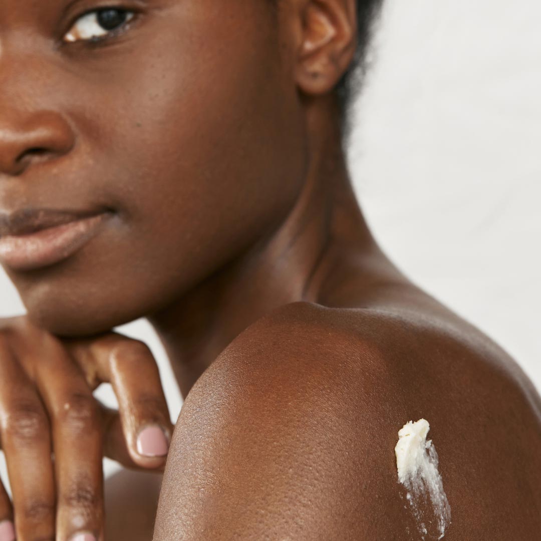 A young woman with bare shoulders and some shea butter applied to the skin