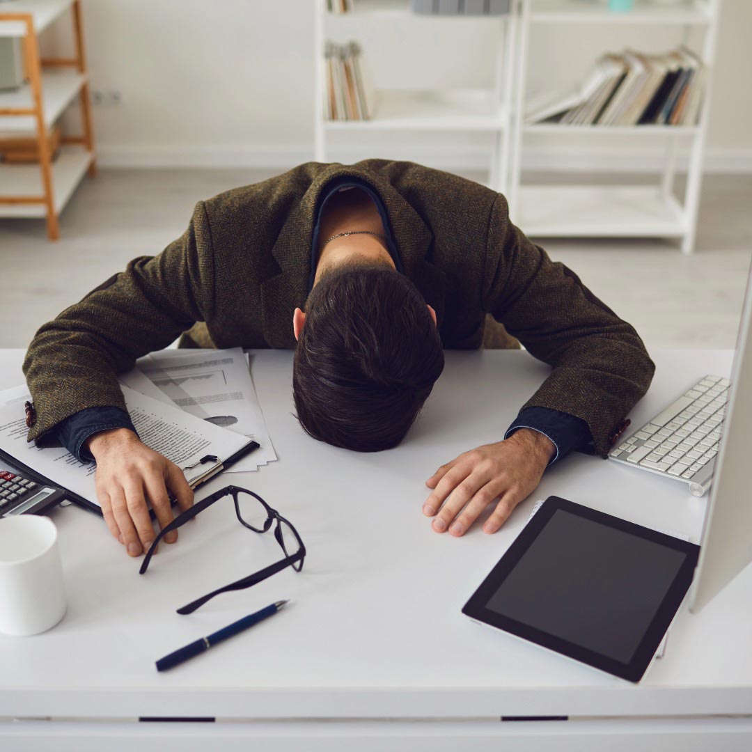 Person with head on desk in office setting