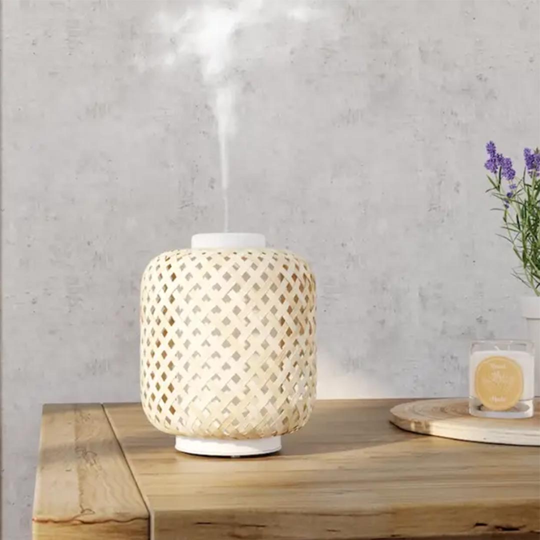 Innobiz Vanelia aroma diffuser standing on a wooden table with Lavender flowers in a pot on the right side