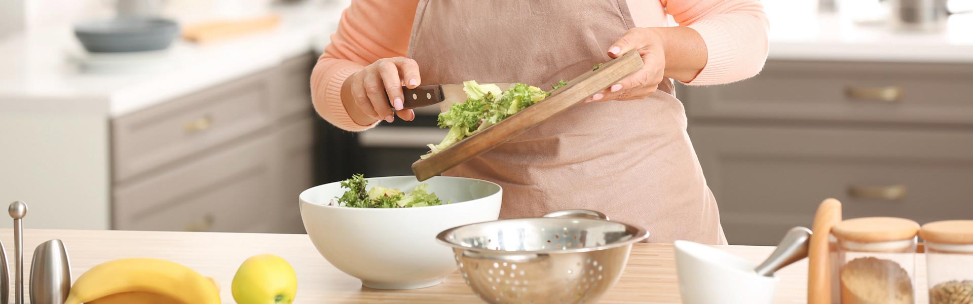 A woman in the kitchen preparing a salad